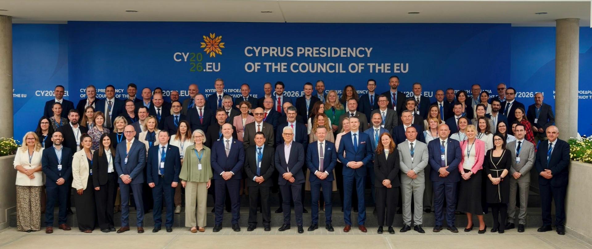Duża grupa uczestników konferencji stoi do wspólnego zdjęcia przed ścianą z napisem „Cyprus Presidency of the Council of the EU”.