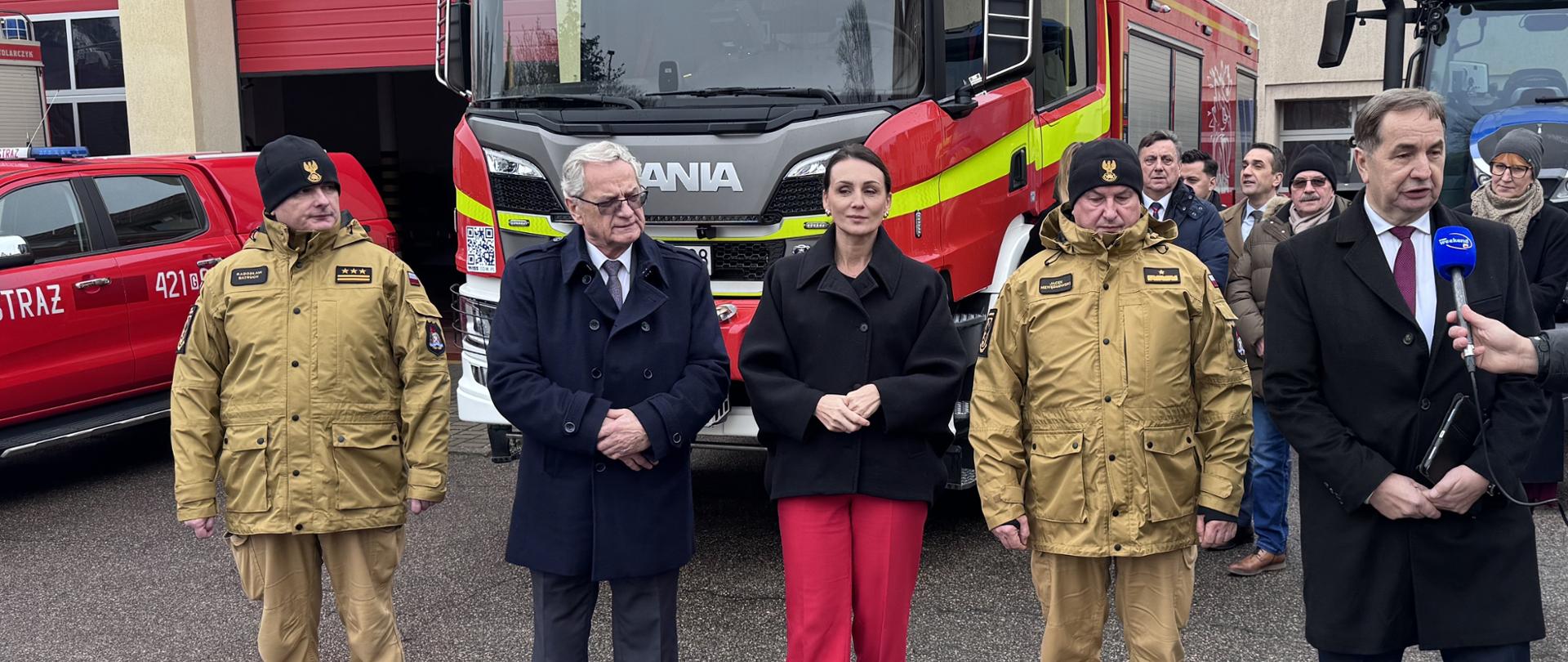 grupa osób stoi przed samochodem ratowniczo gaśniczym, wśród nich jest wojewoda pomorska