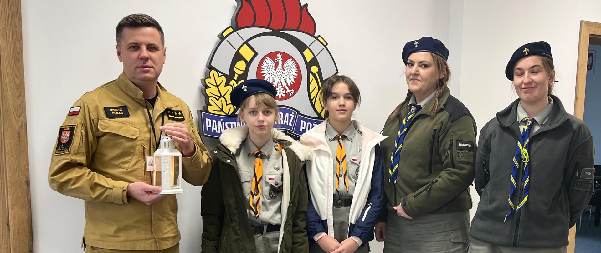 Na zdjęciu Zastępca Komendanta Powiatowego PSP w Wieliczce st. kpt. Robert Ulman trzymający w ręku Betlejemskie Światło Pokoju oraz Harcerze