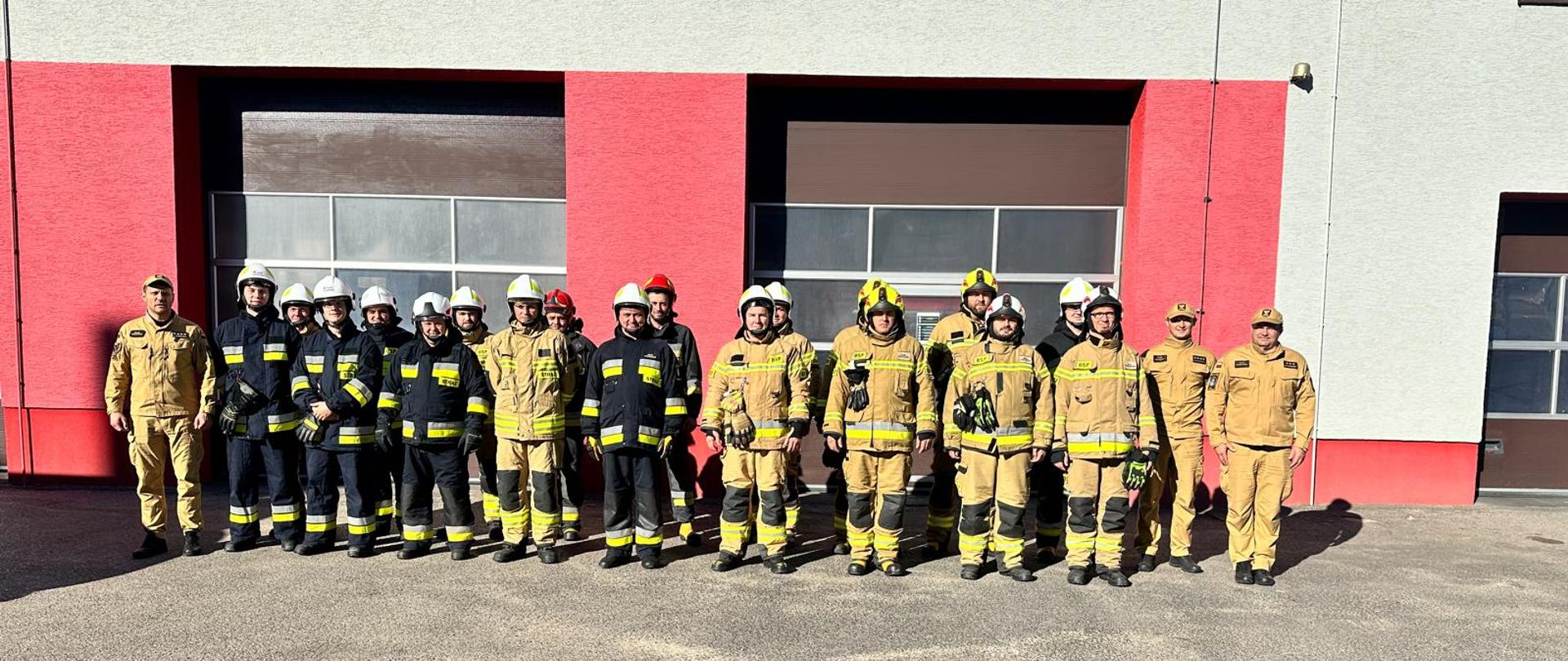 Wspólne zdjęcie strażaków - uczestników szkolenia z komisją egzaminacyjną przed budynkiem komendy. 