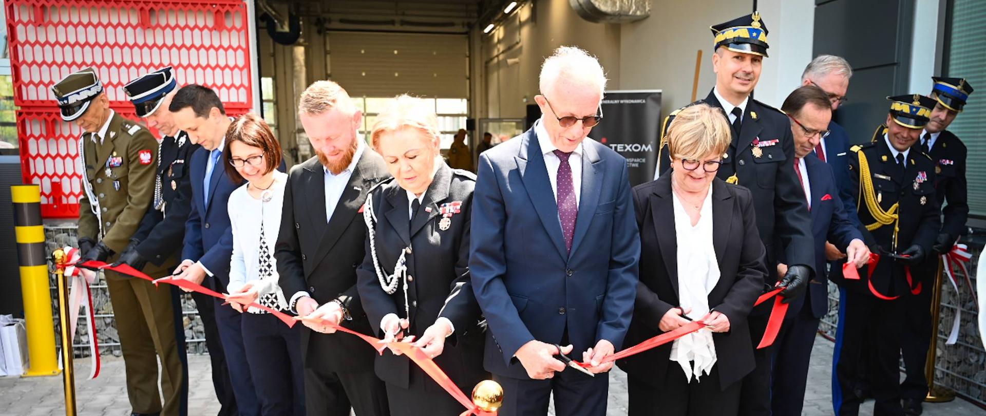 Przedstawiciele władz państwowych, samorządowych oraz PSP przecinają czerwoną wstęgę podczas symbolicznego otwarcia nowej siedziby KP PSP i JRG w Brzozowie.