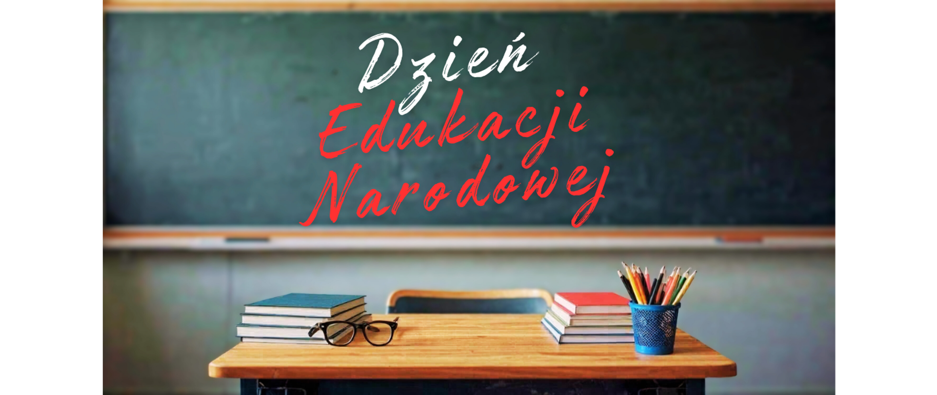 Na biurku książki, okulary oraz przybory szkolne. W tle tablica, na której jest biało-czerwony napis "Dzień Edukacji Narodowej".