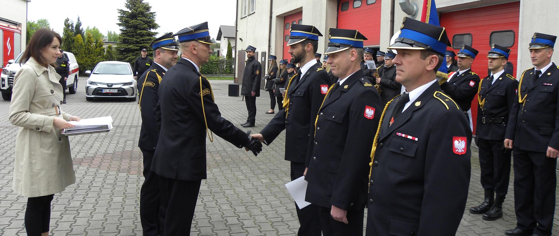 st. bryg. Zbigniew Łyszkowicz wręcza awanse strażakom, po prawej stoją strażacy w dwuszeregu