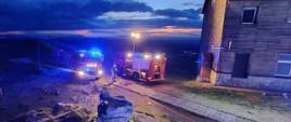 Na zdjęciu znajdują sie dwa pojazdy strażackie oraz linia wężowa do gaszenia pożaru
