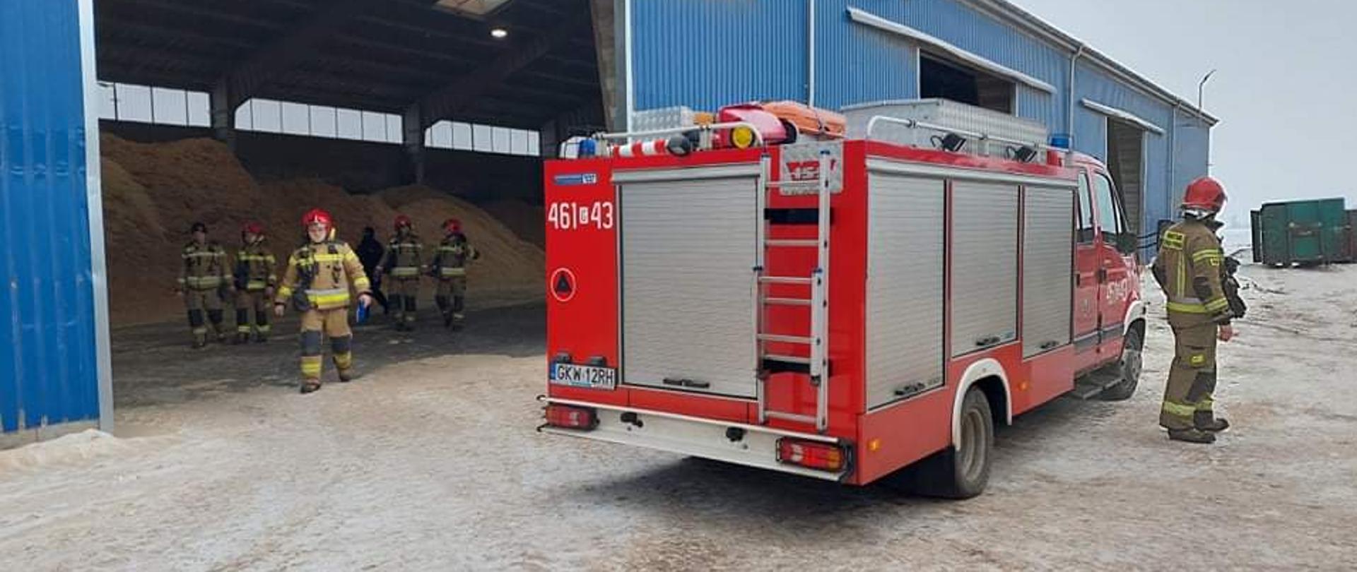 Samochody straży pożarnej stoją przed halą magazynową