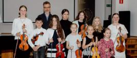Zdjęcie przedstawiające wykonawców popisu klasy skrzypiec mgr Kingi Biesiadeckiej, który odbył się 20 maja 2025 roku w auli szkoły.
