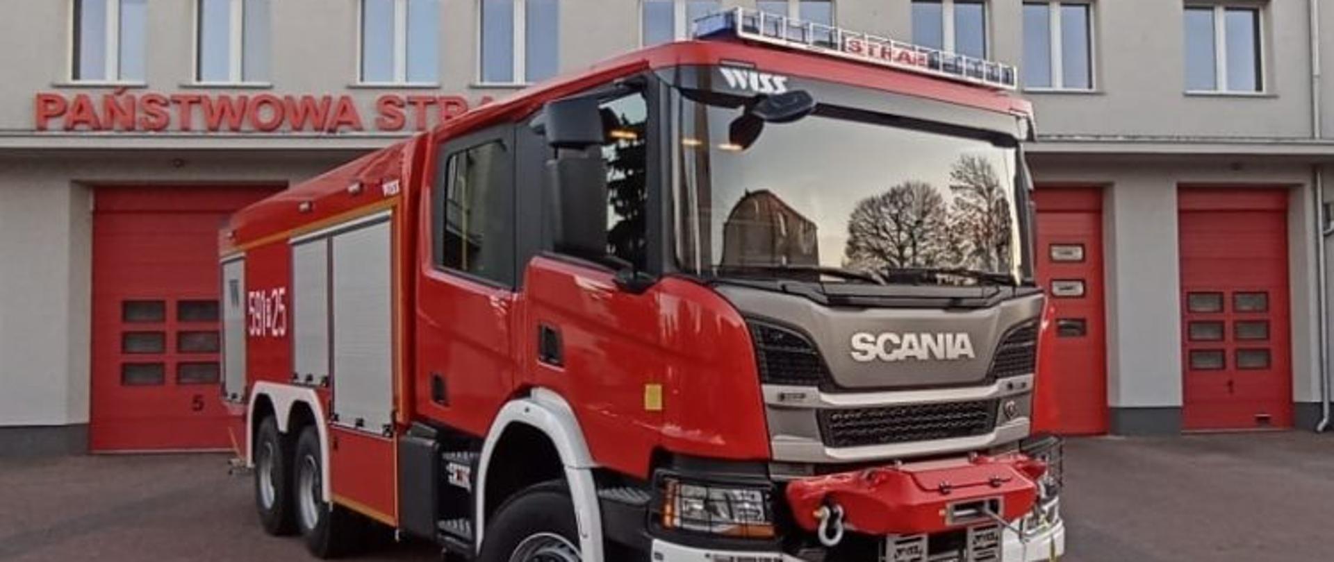 Samochód strażacki na tle Straży Pożarnej