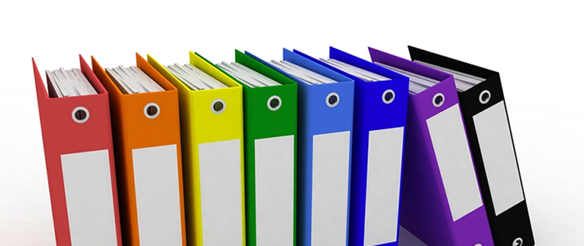 Fotografia przedstawia kolorowe segregatory z dokumentami.