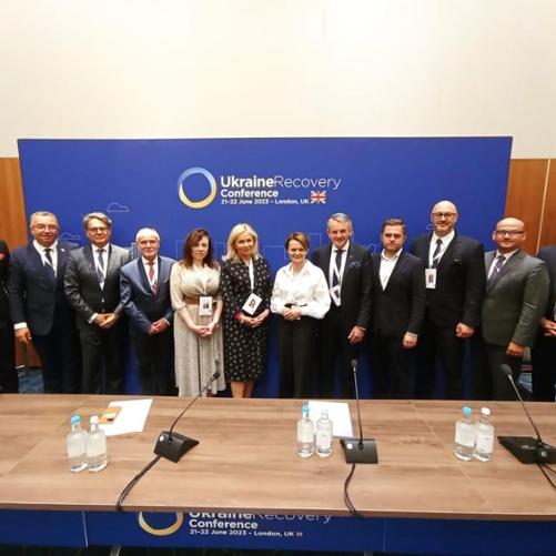 Kilkanaście osób stoi obok siebie w rzędzie.