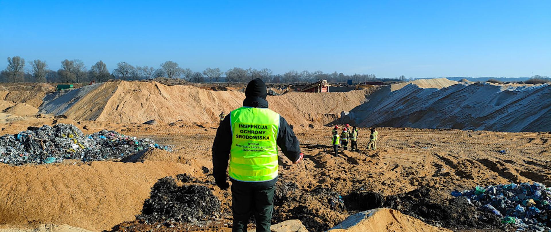 Inspektor przygląda się hałdom odpadów, które udało się wykopać