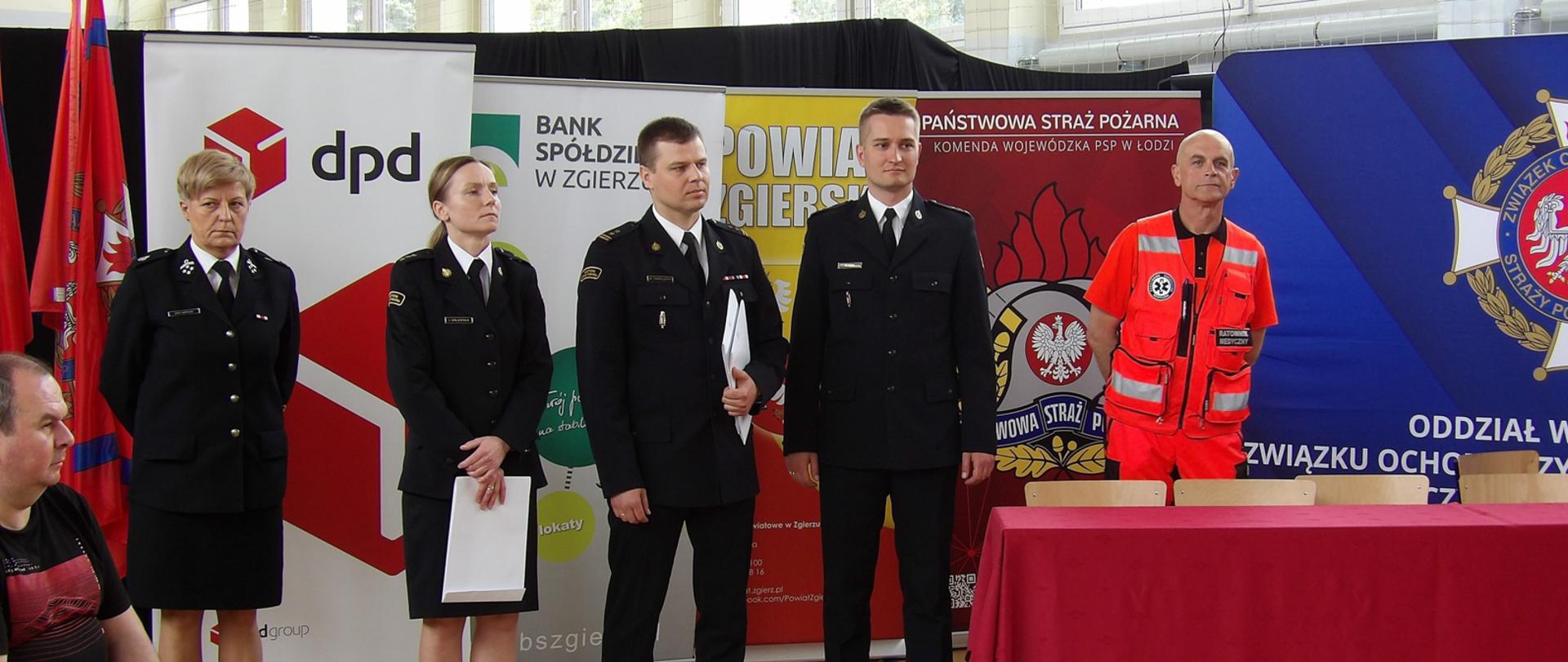 członkowie komisji w sali na tle rollupów