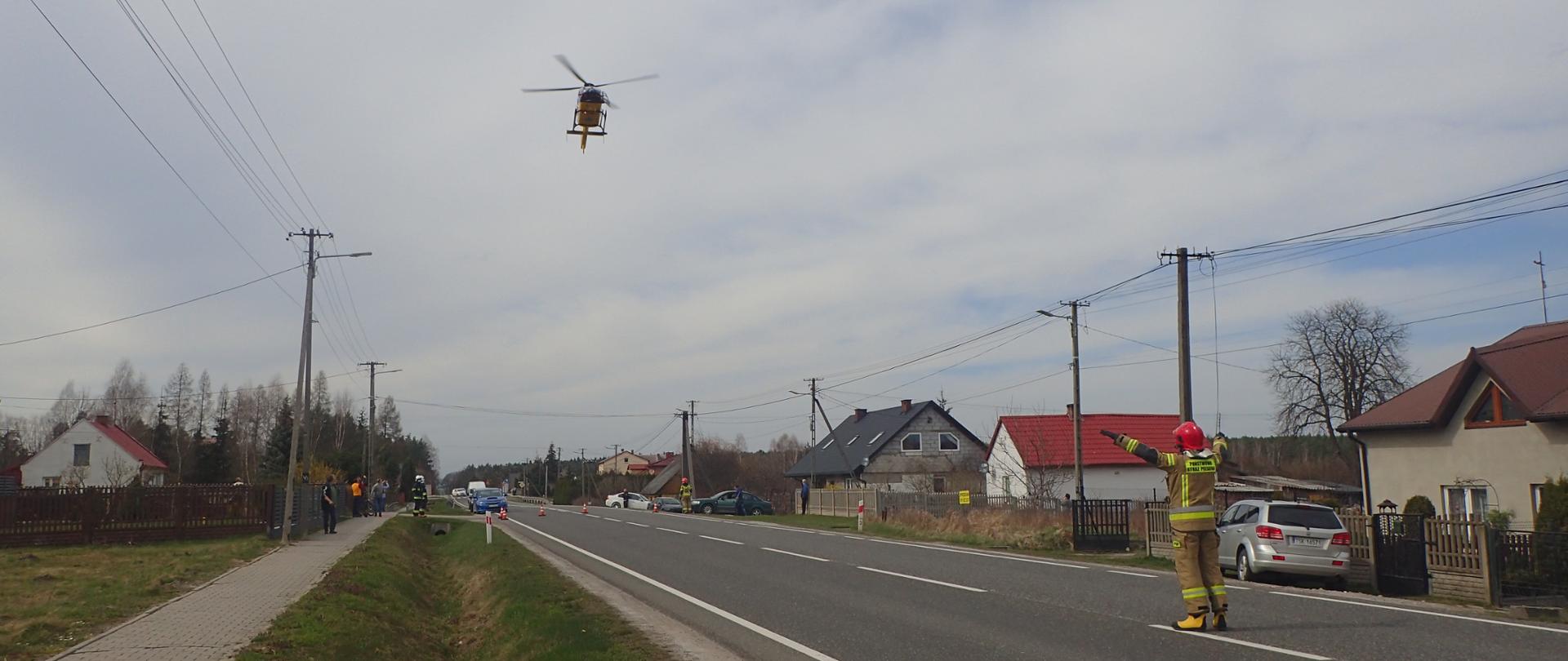 Strażak pomaga w bezpiecznym lądowaniu śmigłowca LPR na drodze 42