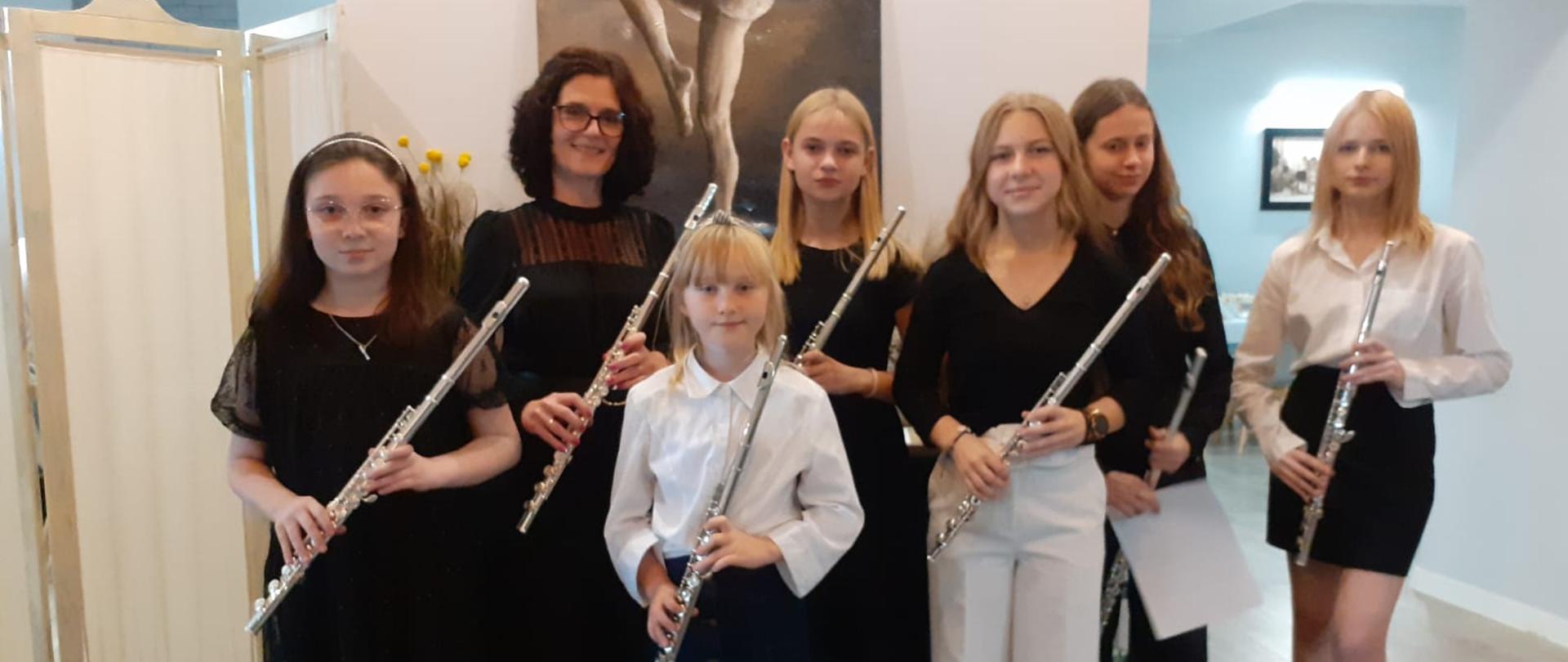 Uczennice wraz z panią Anną Wojtowicz. W tle widoczny obraz zdobiący ścianę nieznanego autorstwa.