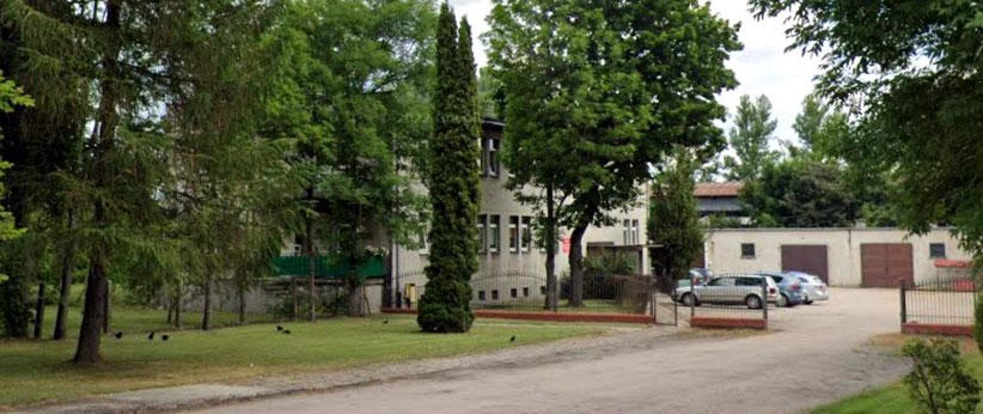 Jednopiętrowy budynek otoczony zielenią. Posiada prostą fasadę i płaski dach. Przed budynkiem znajduje się niewielki parking