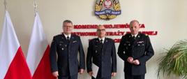 Wręczenie nagrody z okazji 30-lecia służby dla st.bryg. Piotra Juzyszyna przez nadbryg. Jarosława Tomczyka, w tle flagi Polski, kwiat i logo PSP.
Od lewej Komendant Powiatowy PSP w Gryfinie bryg. Sławomir Michalski, po prawej nadbryg. Jarosław Tomczyk, w środku st.bryg. Piotr Juzyszyn