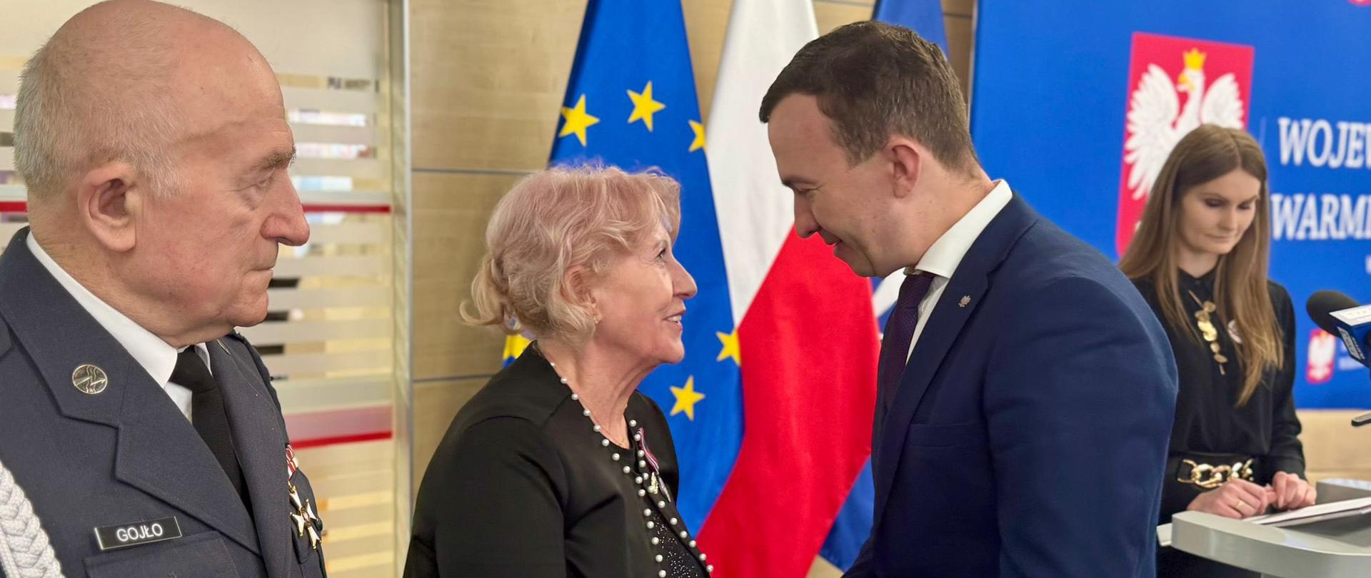 mężczyzna w garniturze, wicewojewoda, podaje rękę kobiecie, gatuluje jej