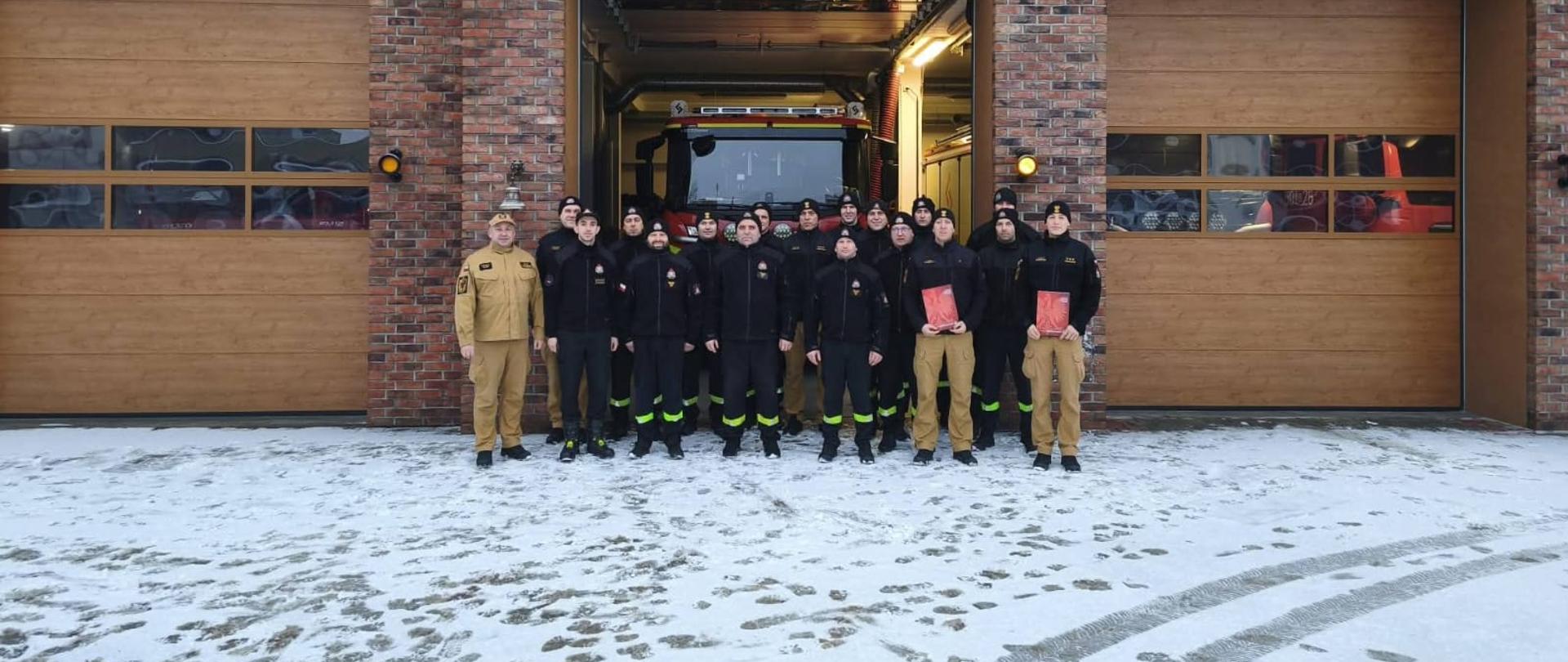 Na zdjęciu wszyscy uczestnicy zbiórki pozują do wspólnego zdjęcia, ustawieni przed budynkiem Jednostki Ratowniczo-Gaśniczej w Pucku.