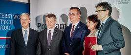 Program dla Bieszczad podpisany. Od lewej stoją Minister Inwestycji i Rozwoju Jerzy Kwieciński, Marszałek Sejmu RP Marek Kuchciński, Podsekretarz Stanu w Ministerstwie Infrastruktury Marek Chodkiewicz, Wicewojewoda Podkarpacki Lucyna Podhalicz i Wicemarszałek Województwa Podkarpackiego Bogdan Romaniuk, który prezentuje czerwoną teczkę z podpisanym dokumentem.