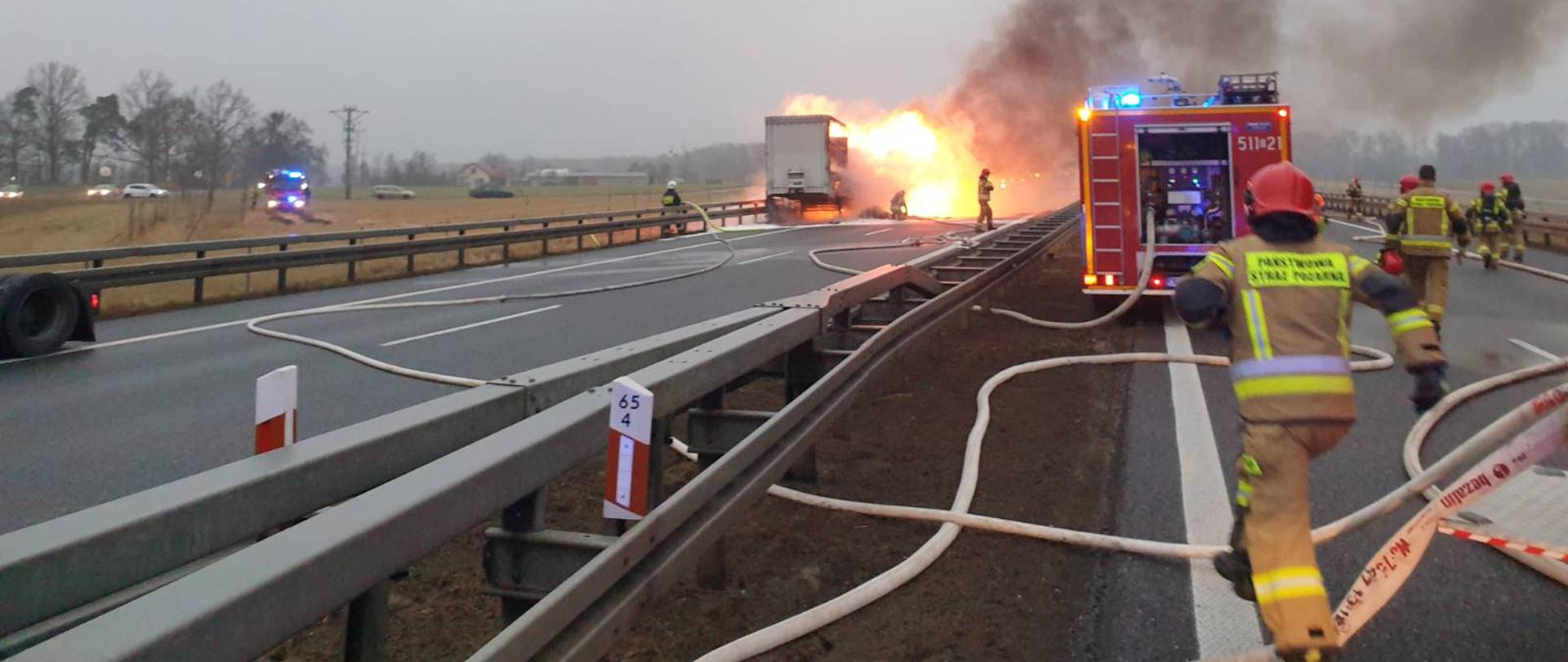 Na zdjęciu widać strażaków, którzy prowadzą działania gaśnicze na drodze S8 gdzie doszło do pożaru świec na naczepie samochodu ciężarowego. 