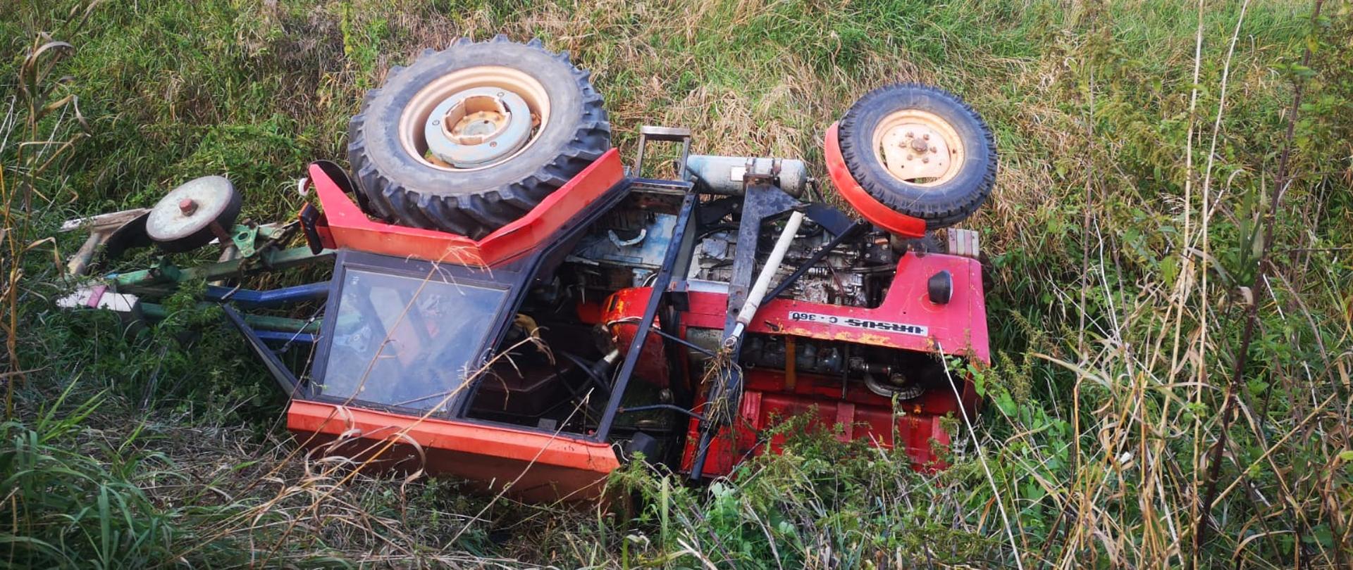 Widać przewrócony ciągnik rolniczy w rowie