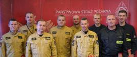 Zdjęcie przedstawia zastępcę Wielkopolskiego Komendanta Wojewódzkiego Państwowej Straży Pożarnej, który wręcza strażakowi PSP podziękowanie. W tle ścianka PSP, strażacy znajdują się w sali sztabowej komendy wojewódzkiej PSP.