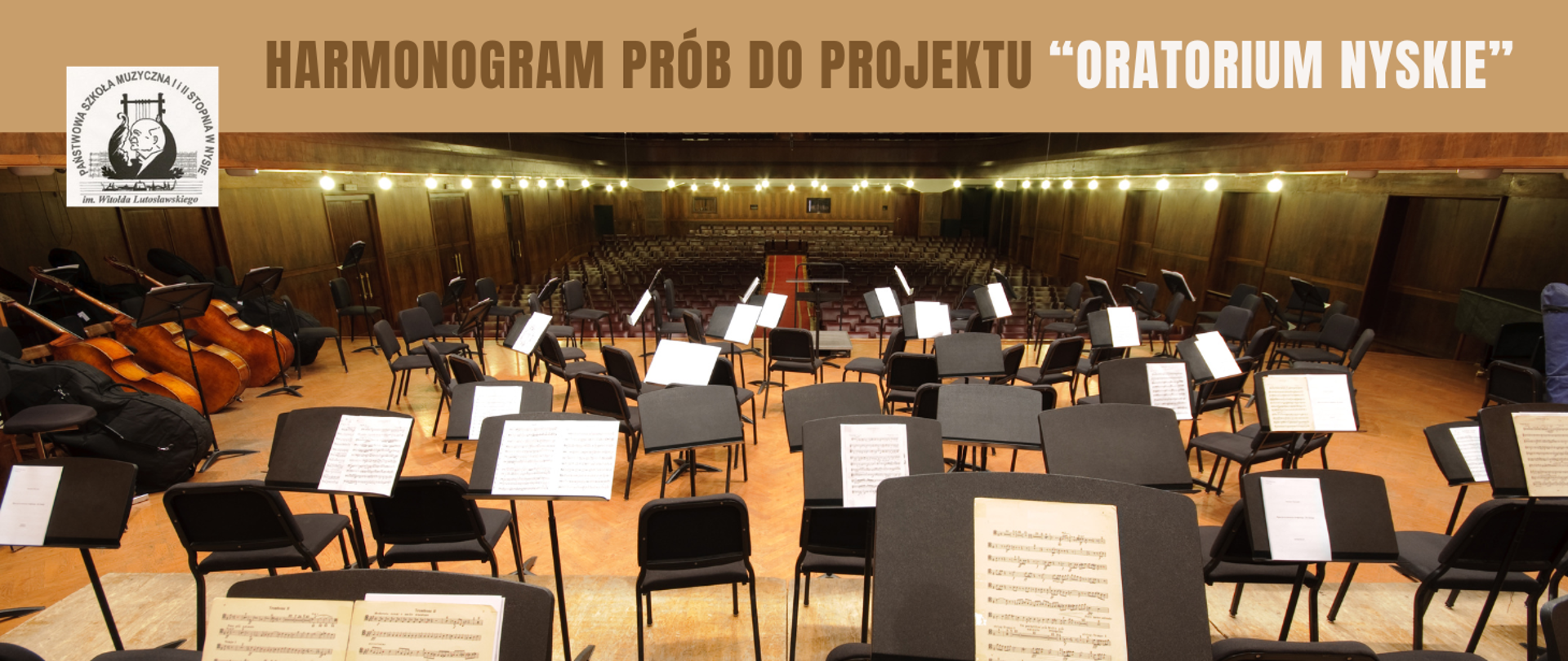 Zdjęcie sali koncertowej widok ze sceny. Dużo czarnych pulpitów oraz krzeseł, na niektórych pulpitach białe kartki z lewej strony pięć kontrabasów dwa w czarnych futerałach trzy środkowe bez futerałów wszystkie oparte o lewą ścianę wnętrze widowni w głębokiej perspektywie oświetlone pod sufitem kulistymi lampami wszystko w kolorach beżu nad zdjęciem beżowy pas z napisem w kolorze ciemniejszym harmonogram prób do projektu oraz w kolorze białym w cudzysłowie Oratorium Nyskie, z lewej strony białe kwadratowe logo szkoły z patronem.