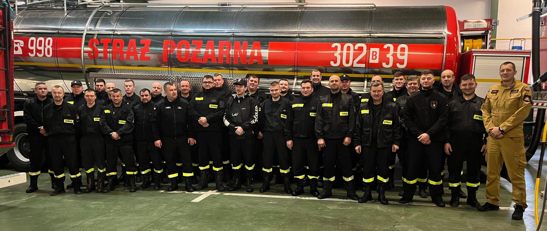 Strażacy na tle samochodu pożarniczego 