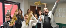 Grupa saksofonistów śmieje się i podnosi instrumenty w górę