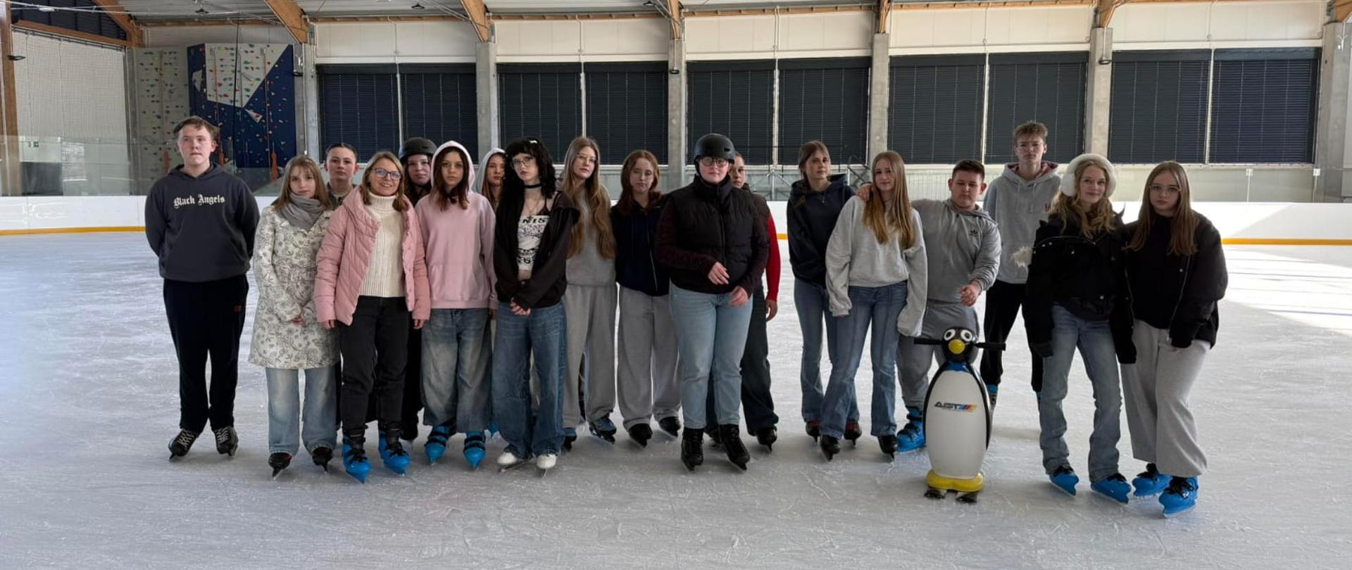 Grupa młodzieży stoi w rzędzie na tafli lodu, pozując do zdjęcia.