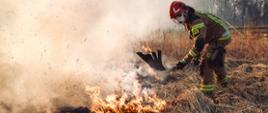 Strażak przy użyciu tłumicy gasi pożar trawy tłumicą