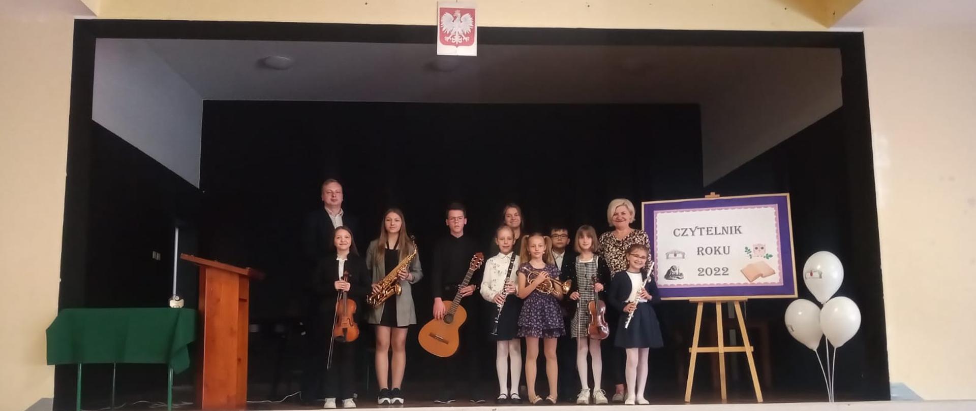 Grupa uczniów i nauczycieli przed koncertem w bibliotece w Szlichtyngowej.