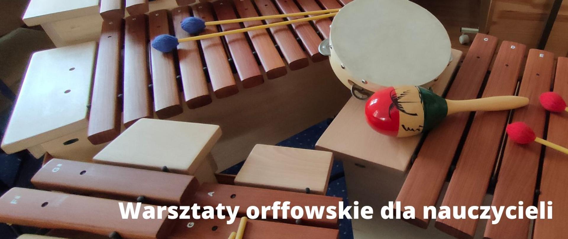 zdjęcie - dziecięce instrumenty perkusyjne: ksylofony z pałeczkami, tamburyn, marakas; fotografia zrobiona w sali lekcyjnej, w dzień; instrumenty stoją swobodnie. Na pierwszym planie biały napis "Warsztaty orffowskie dla nauczycieli" 