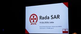 Ekran prezentacyjny w sali konferencyjnej z napisem „Rada SAR, 19.06.2026, Łeba” oraz logotypem Morskiej Służby Poszukiwania i Ratownictwa.