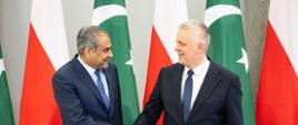 Po prawej stronie zdjęcia minister Tomasz Siemoniak, po lewej stronie zdjęcia minister spraw wewnętrznych Pakistanu Syed Mohsin Raza Naqvi. W tle widać trzy biało-czerwone flagi Polski oraz trzy zielono-białe flagi Pakistanu. 