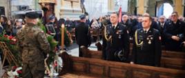 Wnętrze Bazyliki Archikatedralnej w Przemyślu podczas mszy pogrzebowej śp. płk. poż. Stanisława Luli. W pierwszych ławkach stoją funkcjonariusze Państwowej Straży Pożarnej w galowych mundurach, za nimi żołnierz z wieńcem. W tle widać wiernych i poczty sztandarowe.