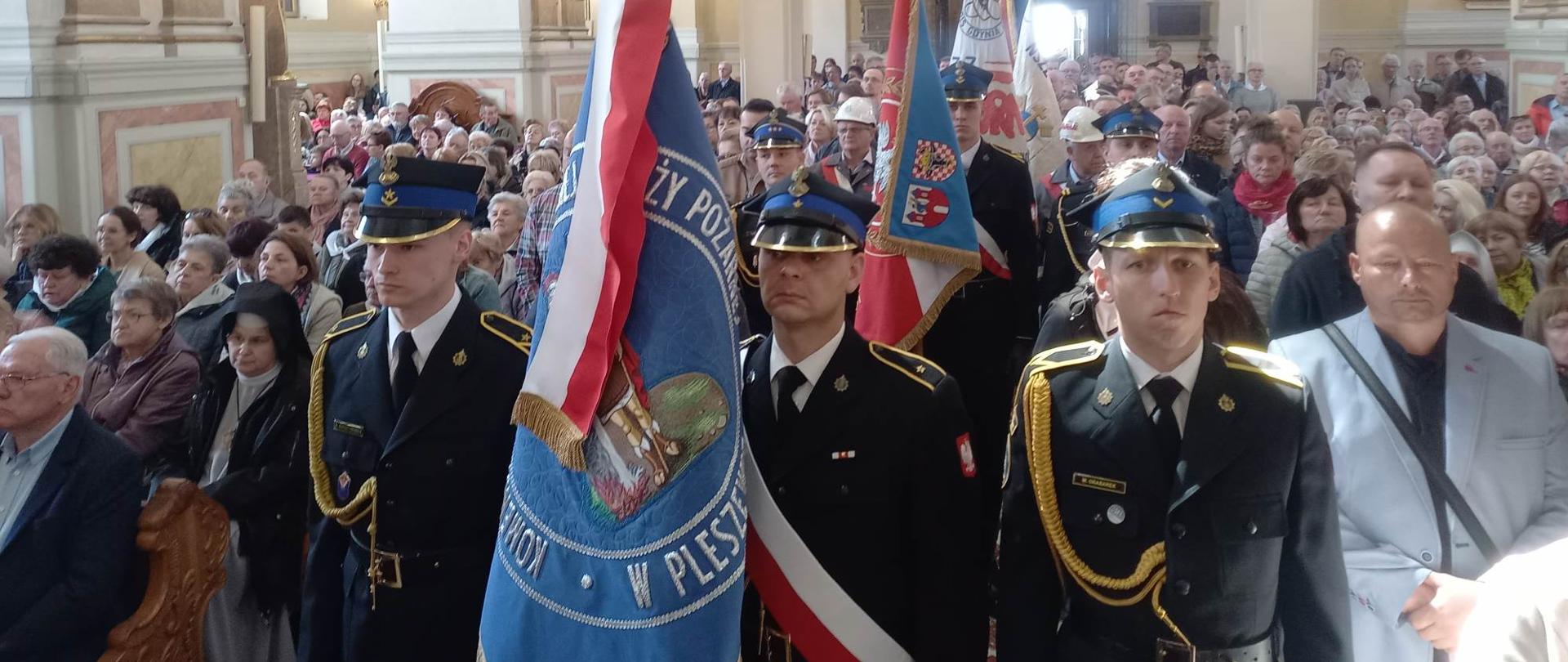 poczet sztandarowy straży pożarnej wraz ze sztandarem stoi w kościele w otoczeniu uczestników mszy