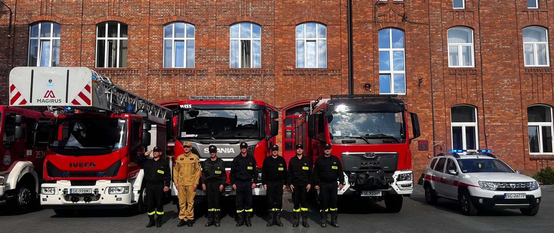 Na zdjęciu przed budynkiem Jednostki Ratowniczo-Gaśniczej numer 3 w Częstochowie ustawione samochody pożarnicze przed nimi ustawieni strażacy w umundurowaniu koszarowym oddają hołd powstańcom.