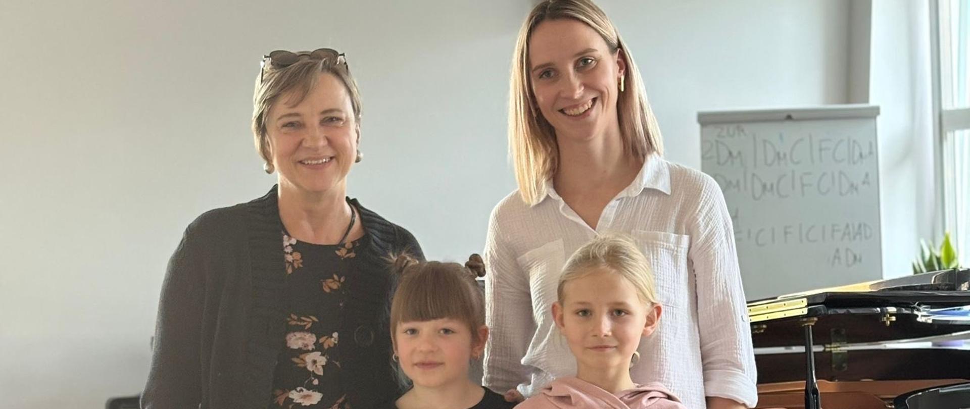 Nauczycielki Elżbieta Lieder i Julianna Bartyzel pozują na stojąco wraz z dwiema uczennicami podczas warsztatów.