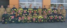 Zdjęcie grupowe. Strażacy trzymają teczki z dyplomem.