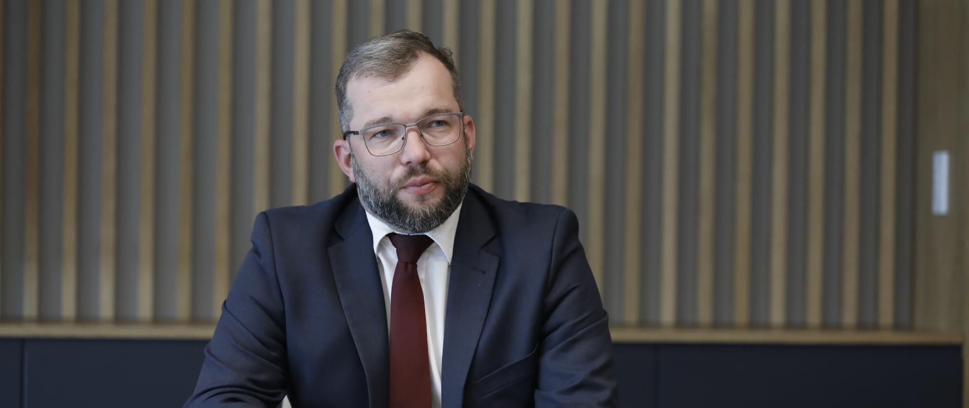 Minister Grzegorz Puda siedzi przy stole.