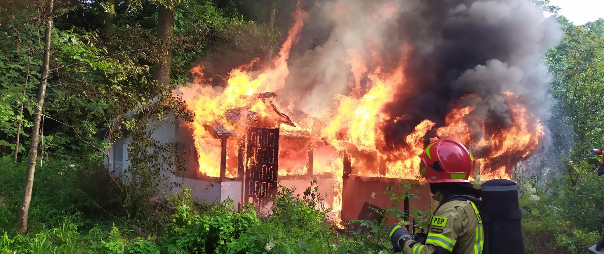 Pożar altany. Strażak gasi pożar.