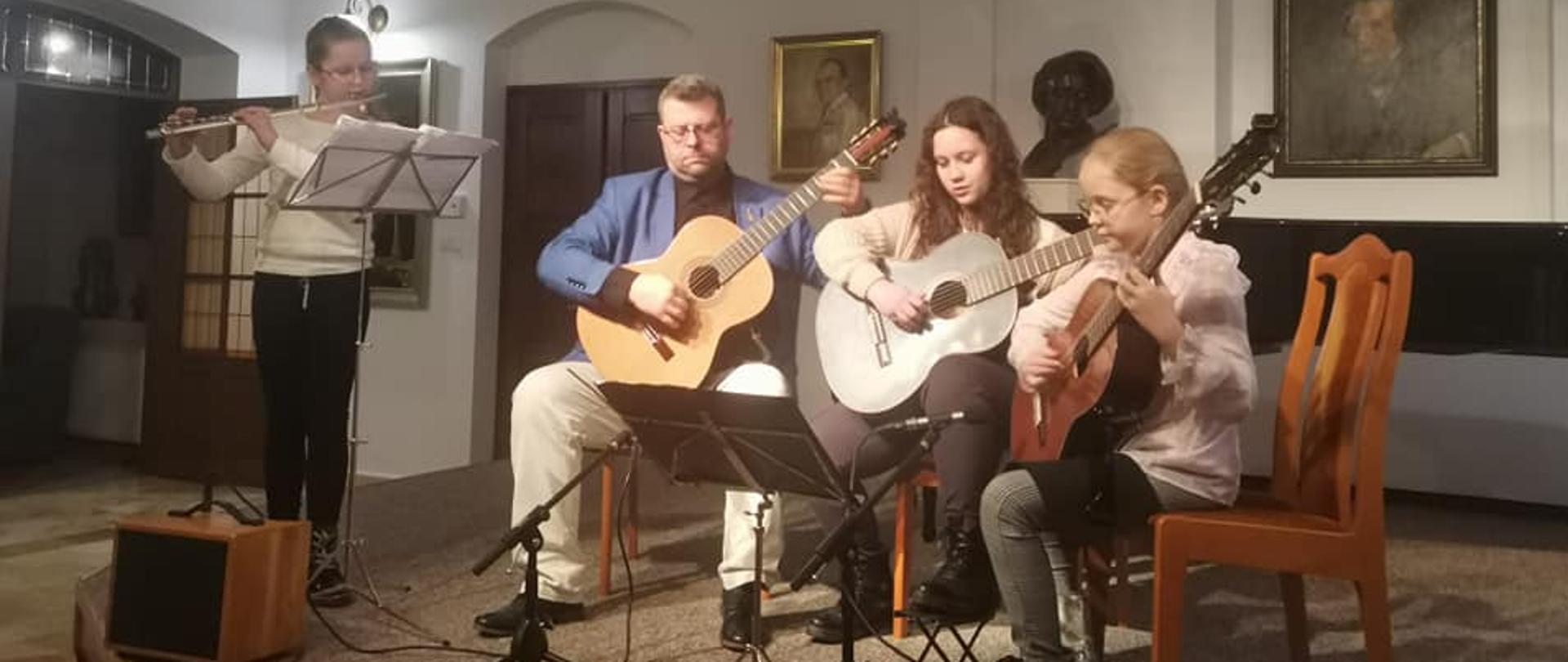 Na zdjęciu uczennica grająca na flecie, oraz dwójka uczennic grająca na gitarze wraz z nauczycielem Witoldem Kozakowskim. Zdjęcie wykonane w siedzibie Fundacji Międzynarodowych Festiwali Chopinowskich - 28 stycznia 2023
