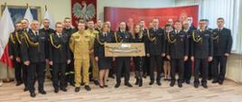 Na zdjęciu widoczny bryg. Maciej Wolański trzymający otrzymaną szablę z okazji przejścia na zaopatrzenie emerytalne pozujący do zdjęcia wraz z funkcjonariuszami i pracownikami cywilnymi KM PSP w Tarnowie
