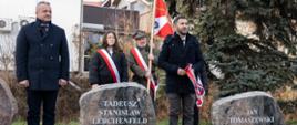 
Cztery osoby stojąca przy kamiennych tablicach upamiętniających bohaterów Powstania Wielkopolskiego
