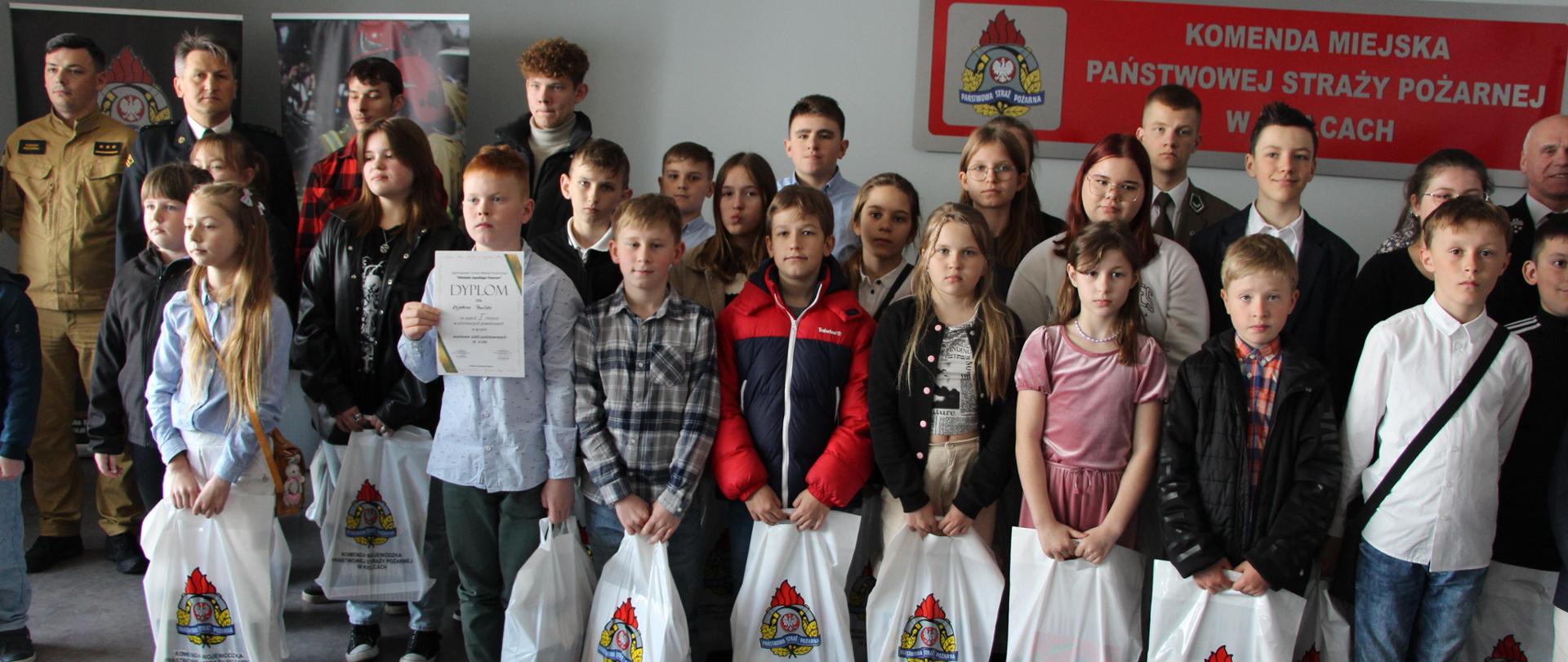 Zdjęcie przedstawia uczestników eliminacji powiatowych OTWP wraz z Komendantem Miejskim PSP w Kielcach bryg Mariuszem Górą, prezesem Zarządu Powiatowego OSP Ireneuszem Żakiem i członkami komisji.