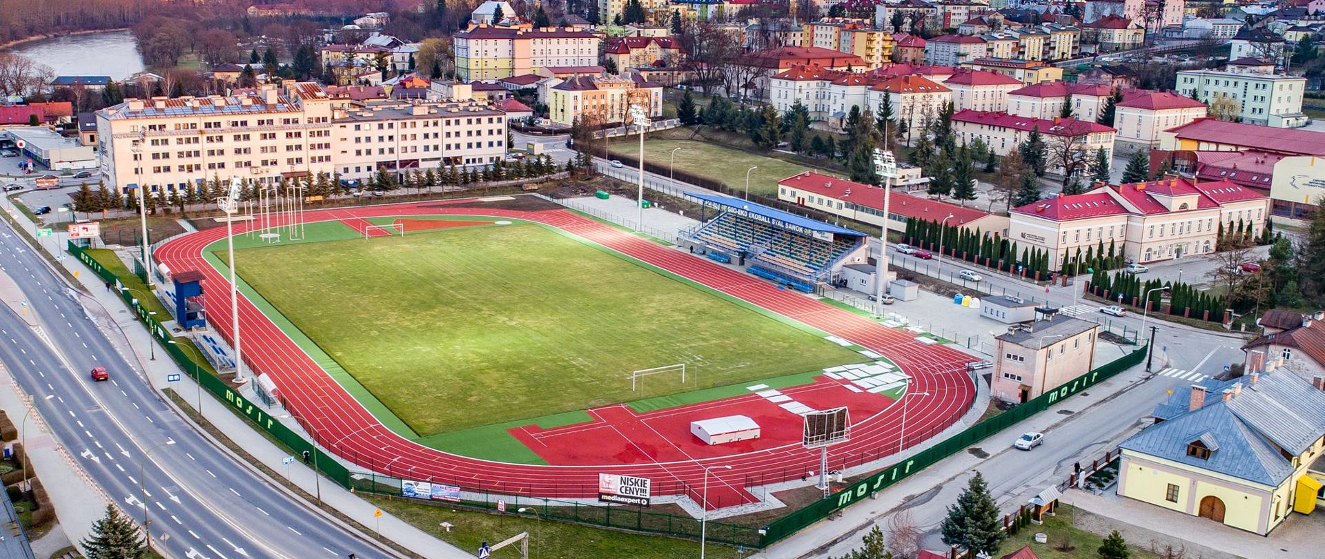 Zdjęcie z lotu ptaka przedstawia stadion. W tle budynki miasta. 