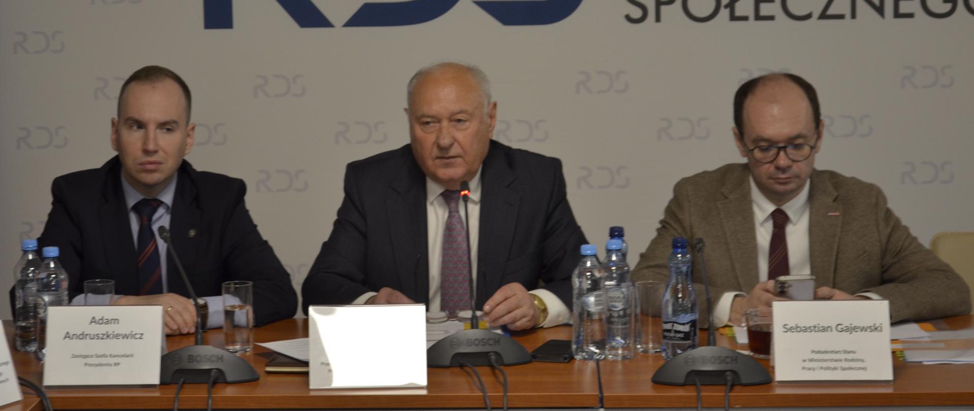 Na zdjęciu widnieje stół prezydialny za którym siedzą od lewej strony: Przedstawiciele Kancelarii Prezydenta RP, Jan Klimek – Przewodniczący Rady Dialogu Społecznego, Sebastian Gajewski – Podsekretarz Stanu w Ministerstwie Ministra Rodziny, Pracy i Polityki Społecznej. W tle siedzących baner z napisem Rada Dialogu Społecznego.