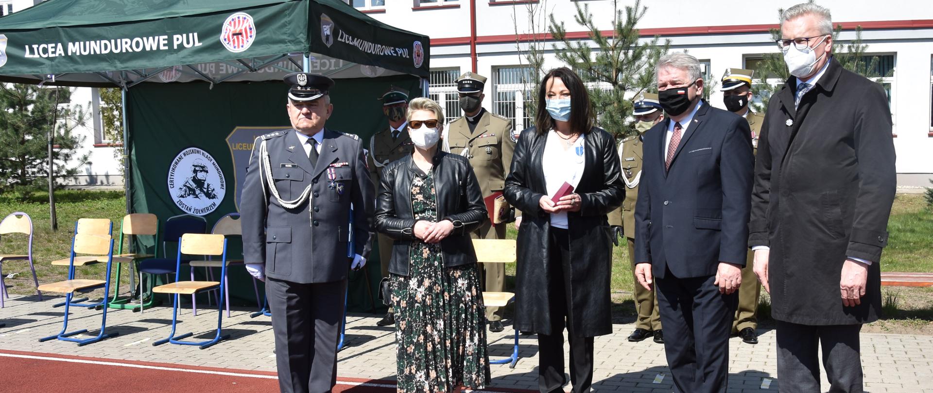 Elegancko ubrane kobiety oraz mężczyźni biorą udział w zakończeniu roku szkolnego
