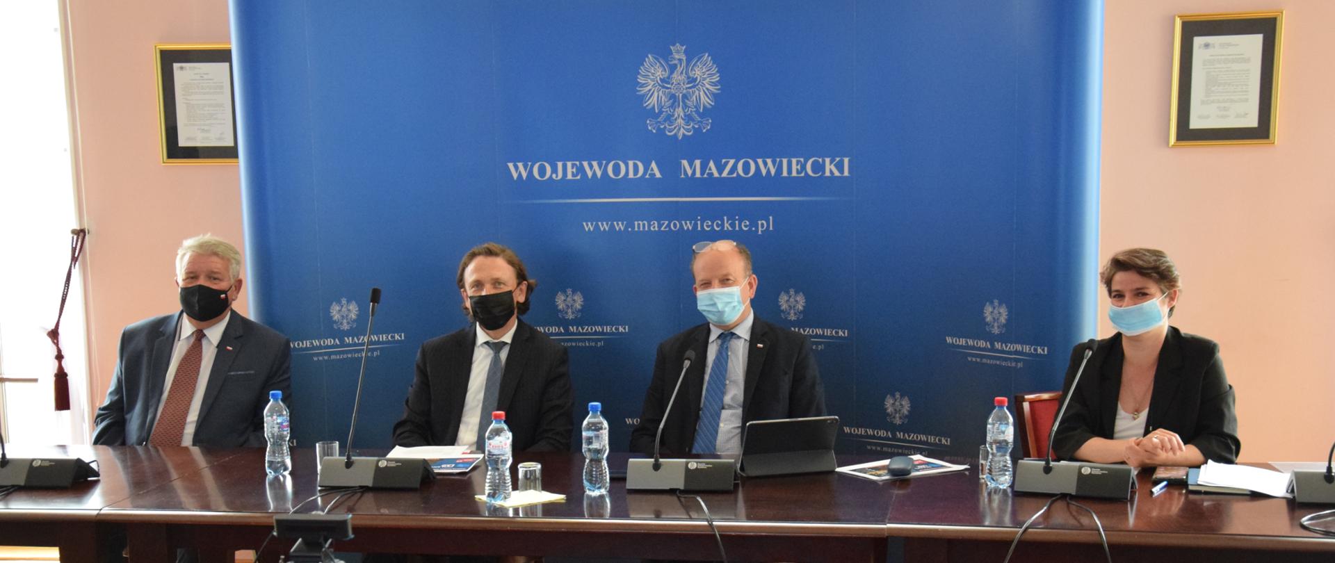 Na zdjęciu znajdują się cztery osoby siedzące za stołem