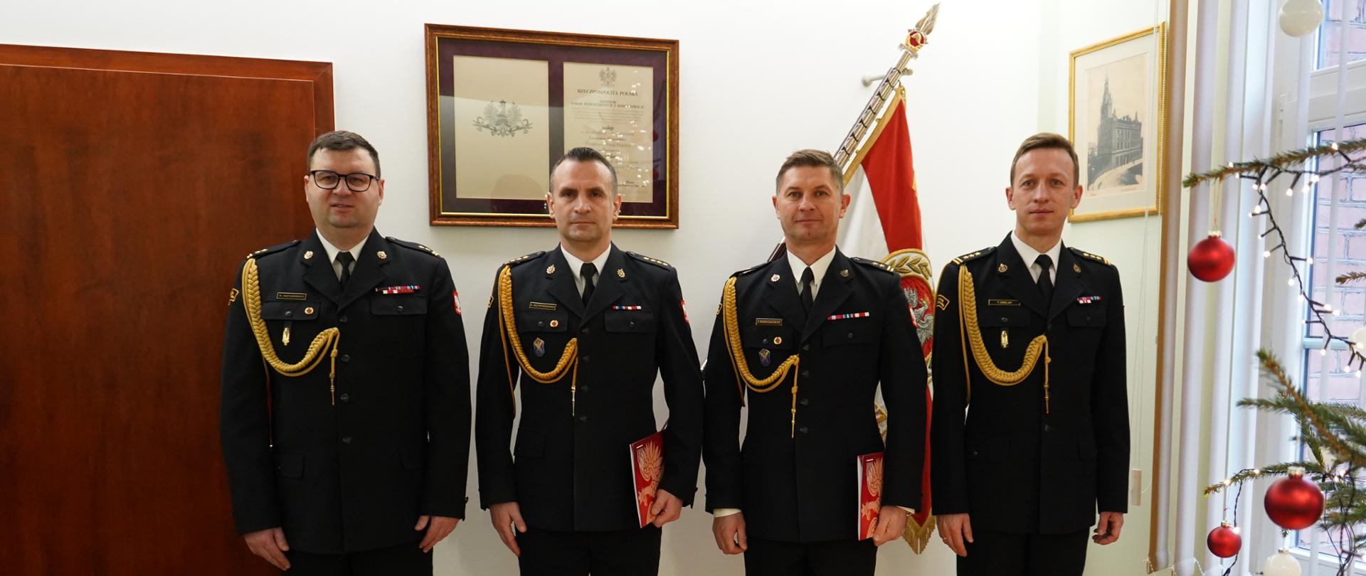 Strażacy stoją ba tle sztandaru